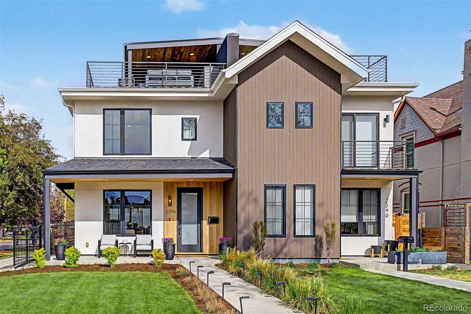 Modern three-story duplex with wood accents and rooftop railings on a Denver corner lot