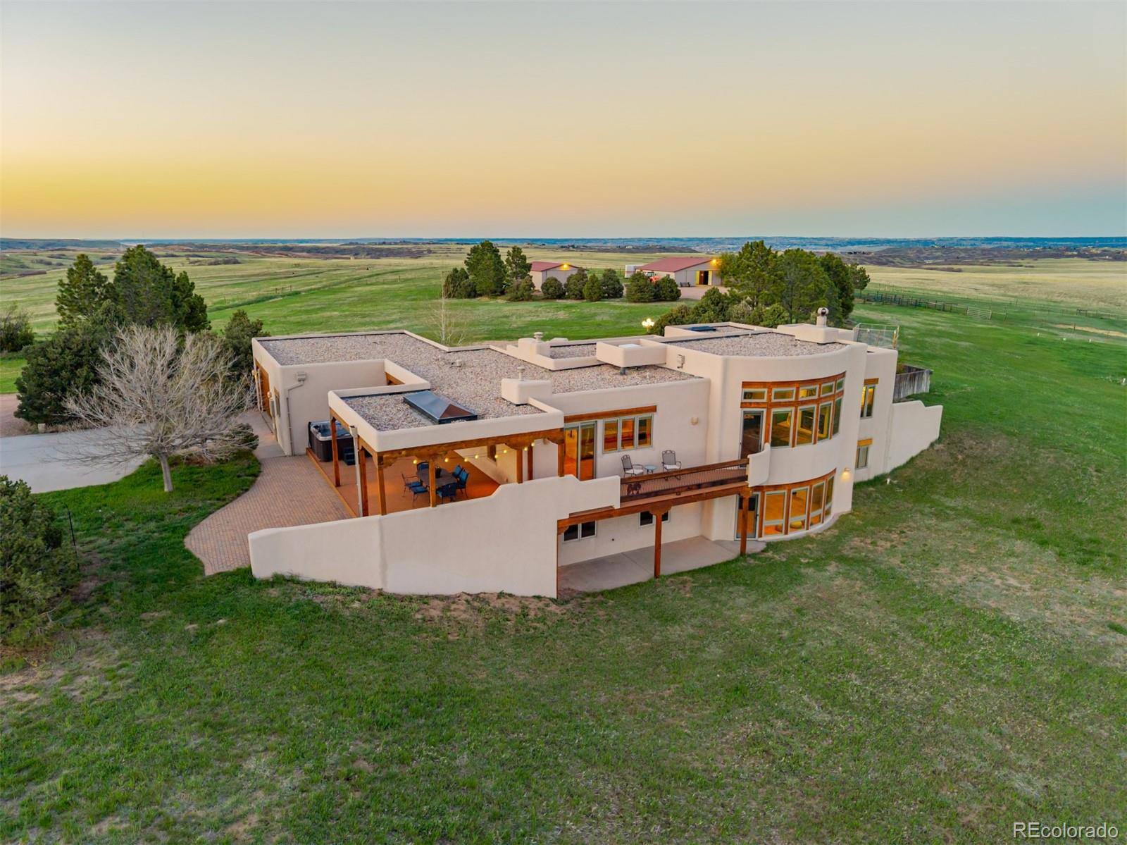 Aerial view of an adobe ranch home and courtyards at sunset in Castle Rock