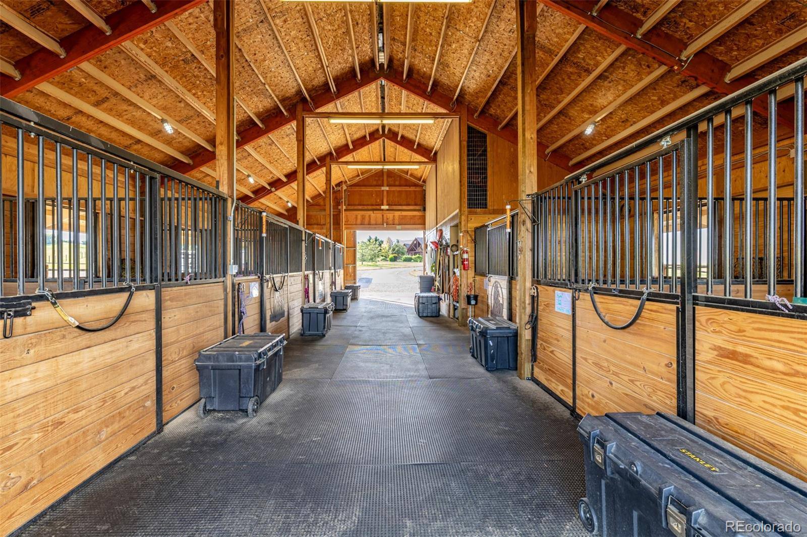 Sunlit center aisle of a six-stall timber horse barn in Franktown