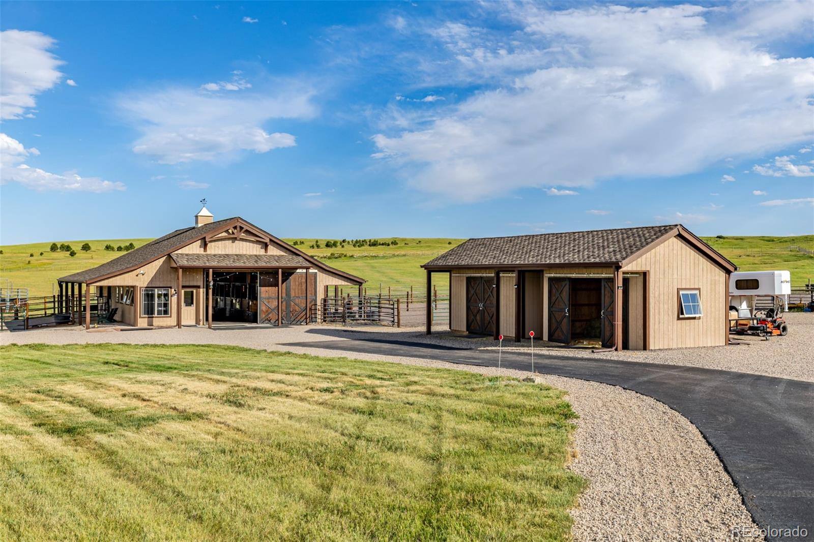 Horse barn with cupola beside a hay barn on a Franktown equestrian estate