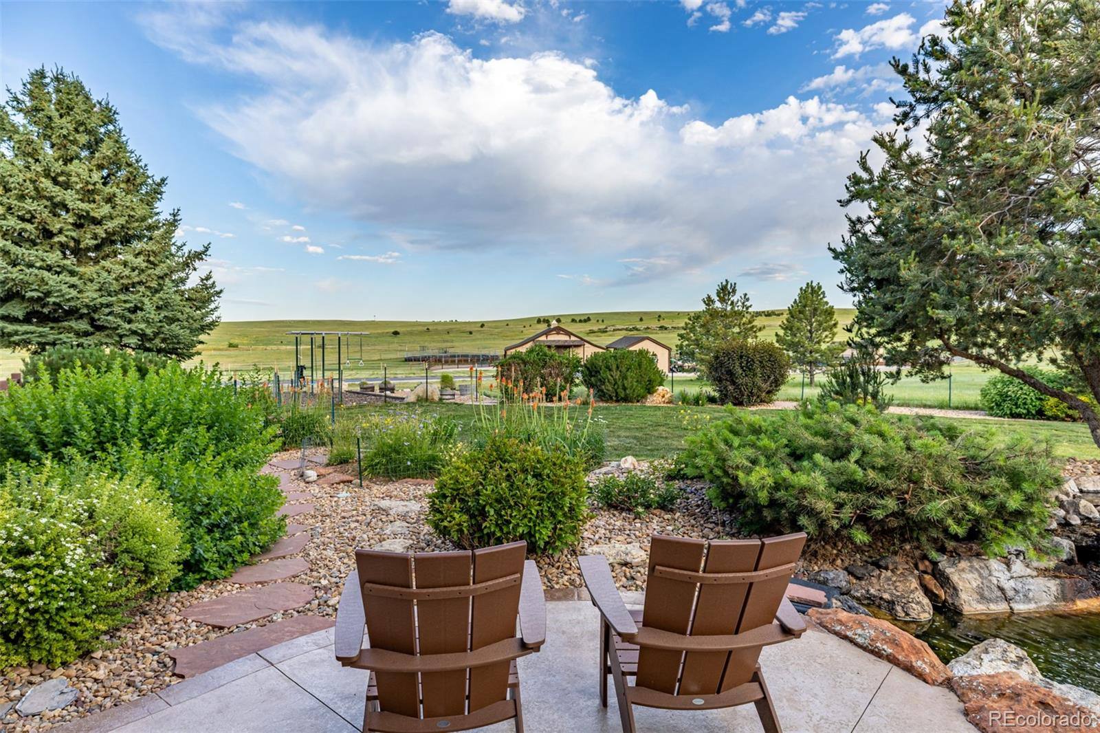 Patio chairs overlooking fenced pastures and a barn