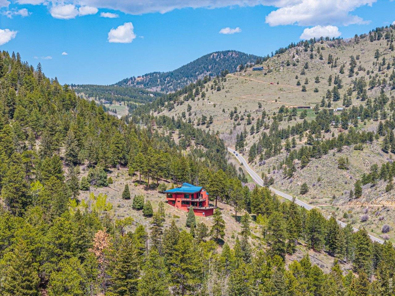Aerial view down the canyon with the home small against miles of forested foothills